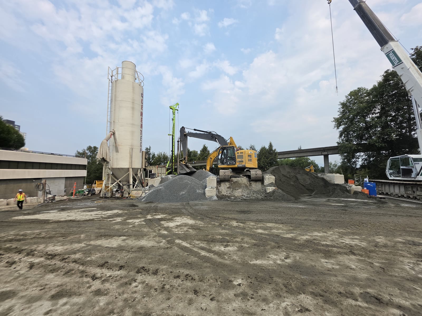 Cement silo and aggregate stockpiles set up on site beside a drilling rig