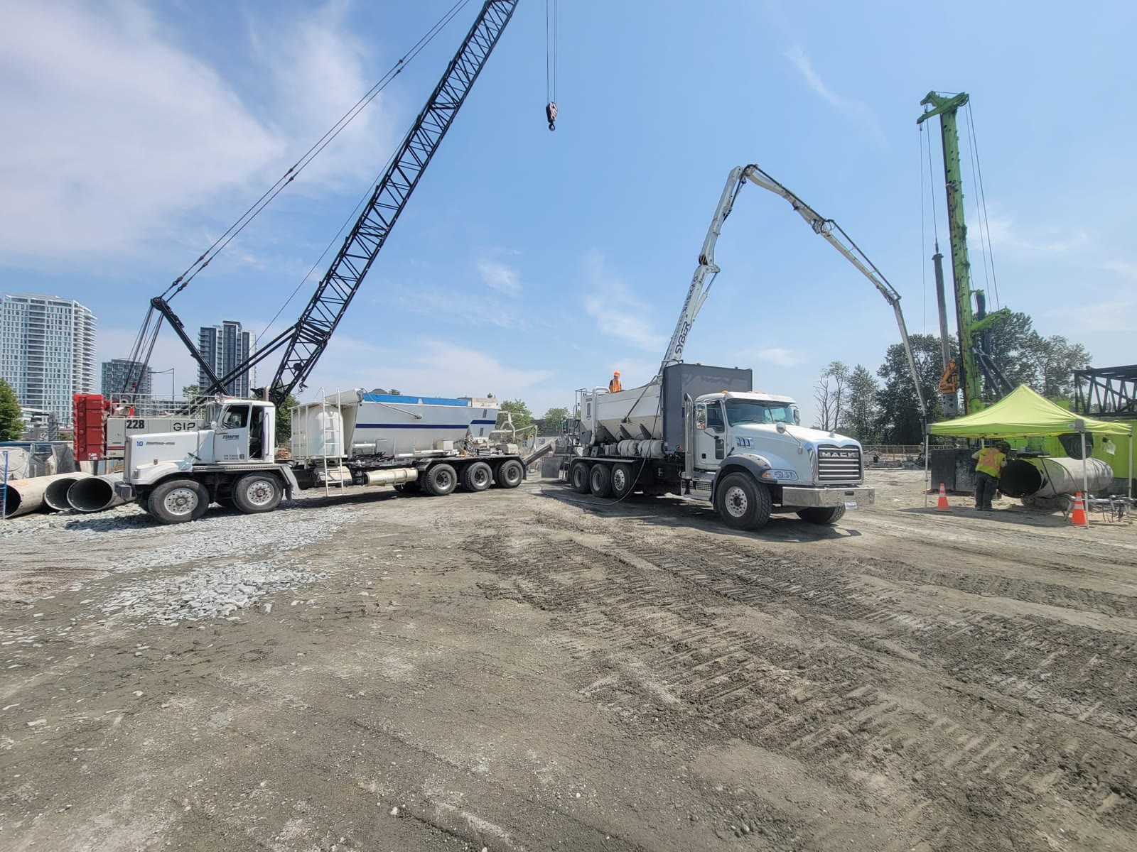 Crane, reload trailer and volumetric mixer staged across an open construction site