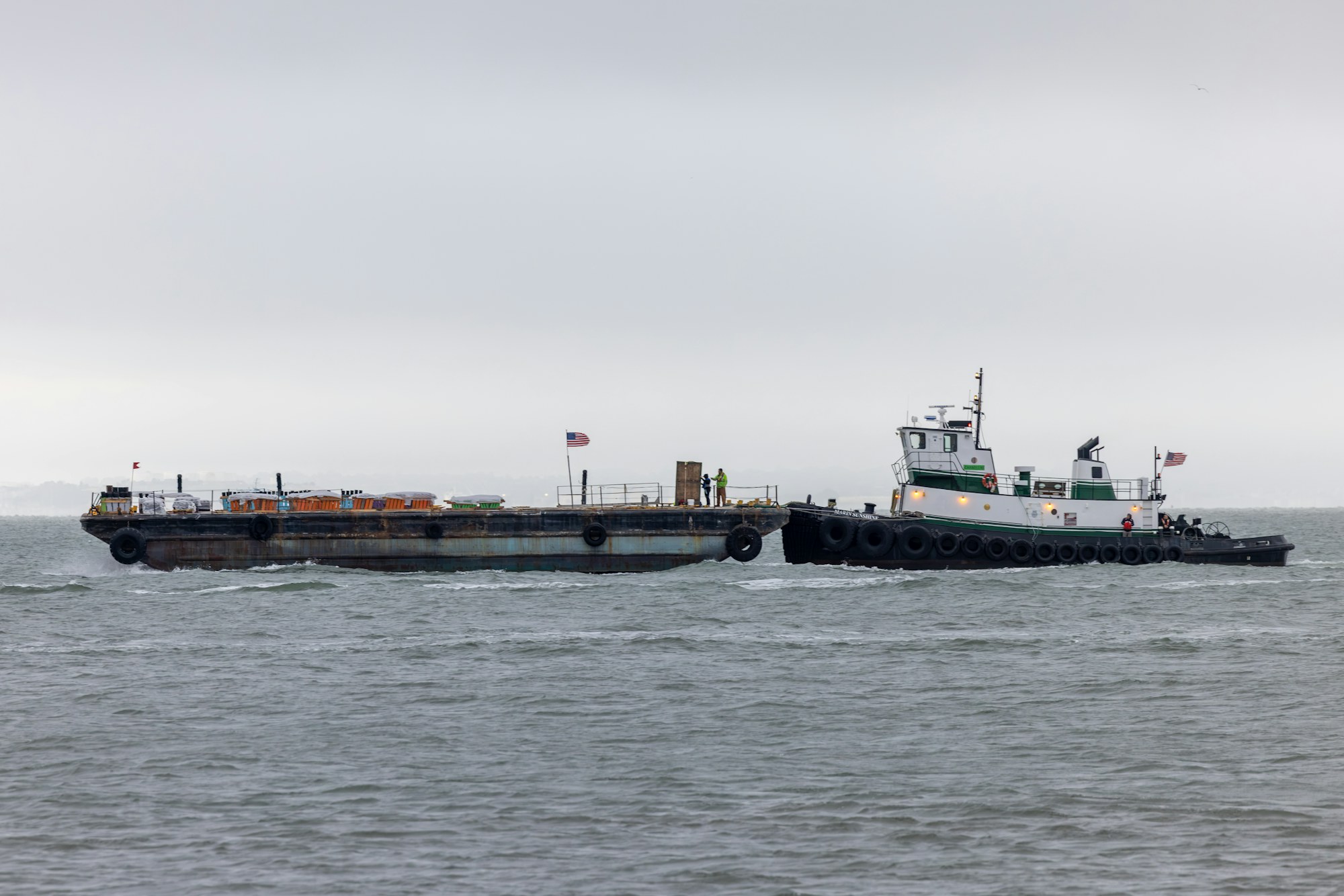 Tugboat pushing a loaded industrial barge across open water